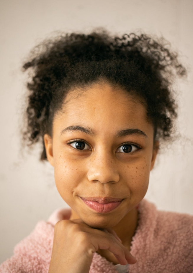 Smiling teenage girl with freckles, wearing a pink wool sweater